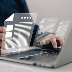 Eine Hand mit einem ePen und eine Hand am Laptop. Es sind digitale Formulare über dem Laptop.